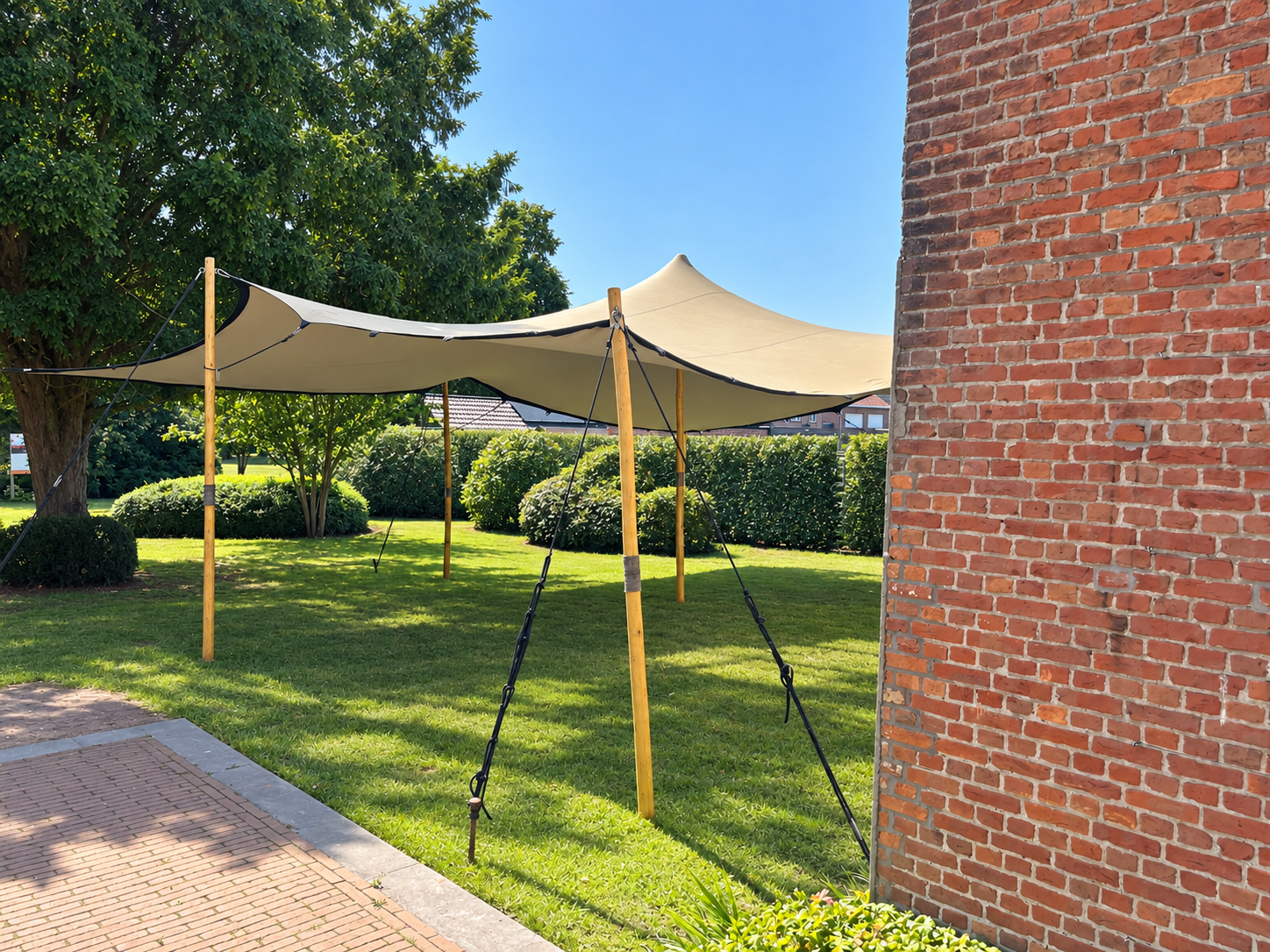 Beige stretchtent met houten palen in een zonnige tuin